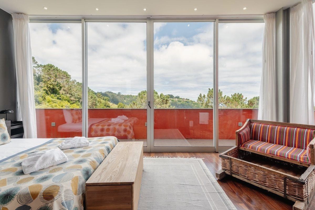 Master bedroom, a wall of glass onto the orange terrace and the hills