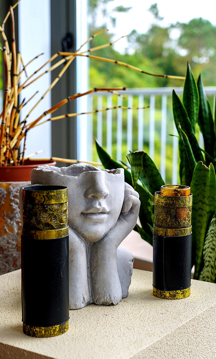 A stone face planter between two gold-banded candle holders, the terrace rail and forest behind